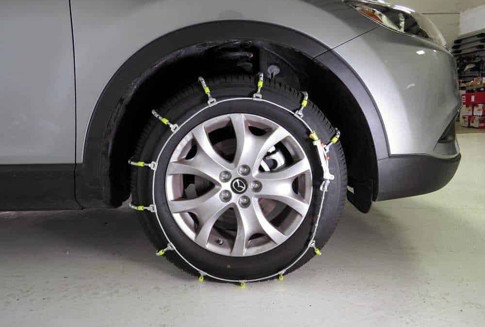 Ruota di un'auto con pneumatici da neve montati, dotata di catene da neve installate per una maggiore sicurezza invernale.