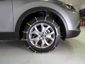 Ruota di un'auto con pneumatici da neve montati, dotata di catene da neve installate per una maggiore sicurezza invernale.