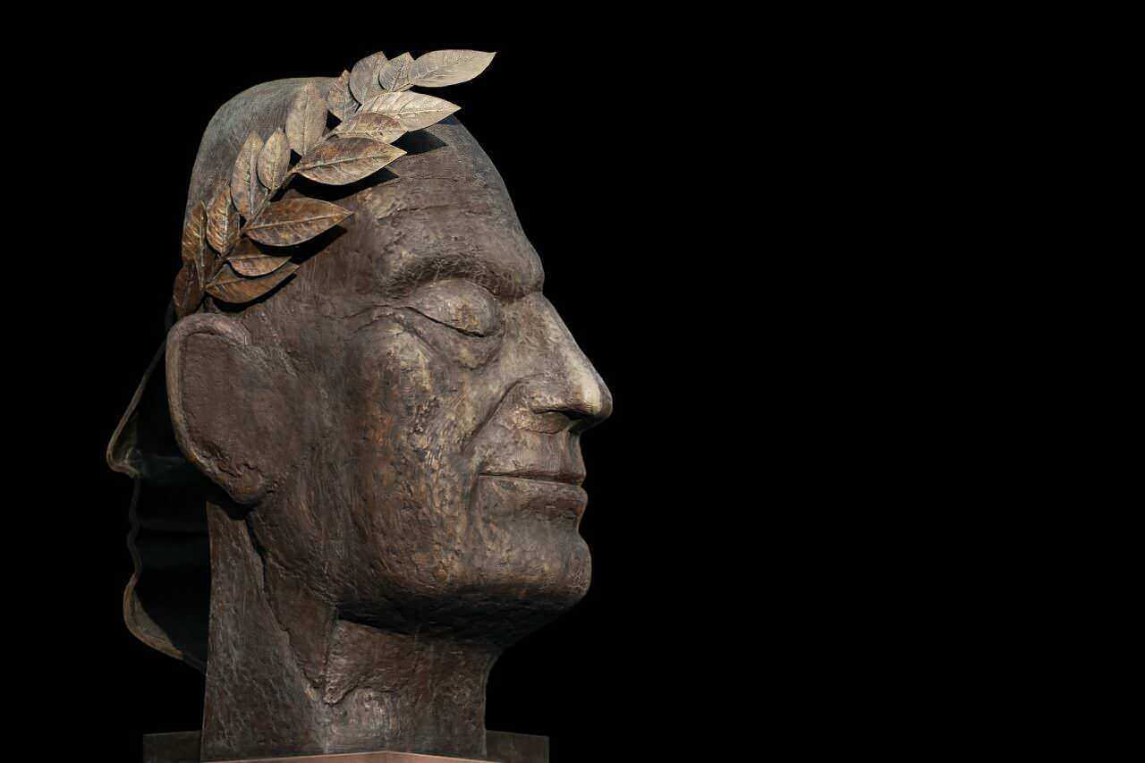 Circo massimo di roma: Bronzo di una testa di anziano con foglie di alloro in testa, simbolo di saggezza e vittoria, su sfondo nero, rappresenta il rispetto delle persone anziane e l'importanza della memoria storica.