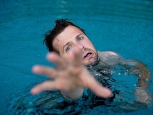 Boscaiolo che affoga in piscina, immagine di un uomo che si trova in difficoltà in acqua con espressione di paura.