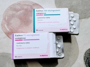 Eutirox 75 e 100 microgrammi compresse, farmaci per il trattamento dell'ipotiroidismo, confezioni con blister di compresse bianche e confezioni colorate, su sfondo neutro.