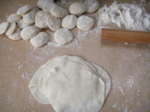 Tridioni di pasta fresca con farinata, palline di impasto e matterello su superficie infarinata, pronti per essere stesi.