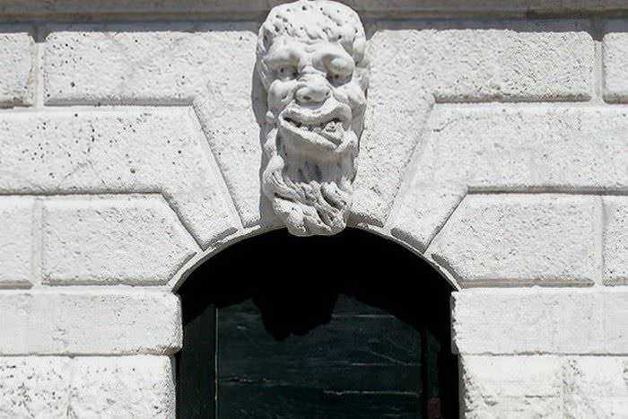 Barba e volto di pietra scolpiti sulla facciata di un edificio storico, decorazione architettonica distintiva.