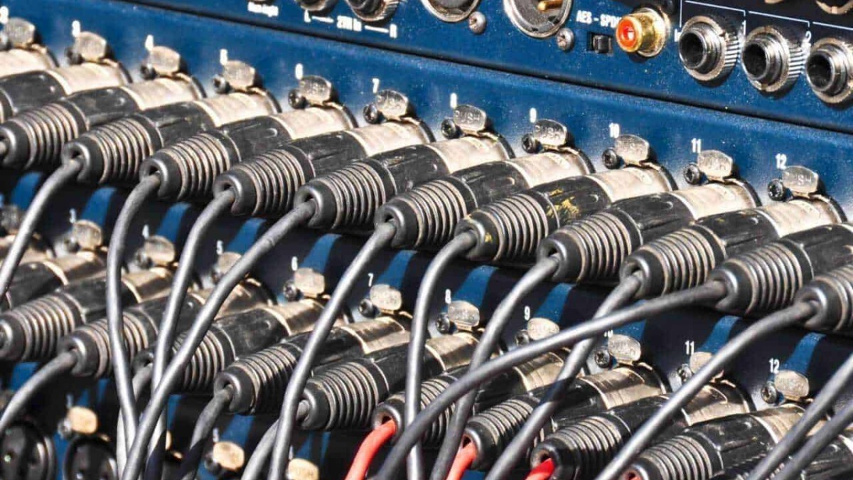 Mixer audio professionale con cavi collegati, tecnologie di registrazione audio, attrezzature per studi di registrazione, strumenti audio di alta qualità.