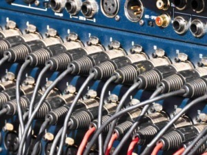 Mixer audio professionale con cavi collegati, tecnologie di registrazione audio, attrezzature per studi di registrazione, strumenti audio di alta qualità.