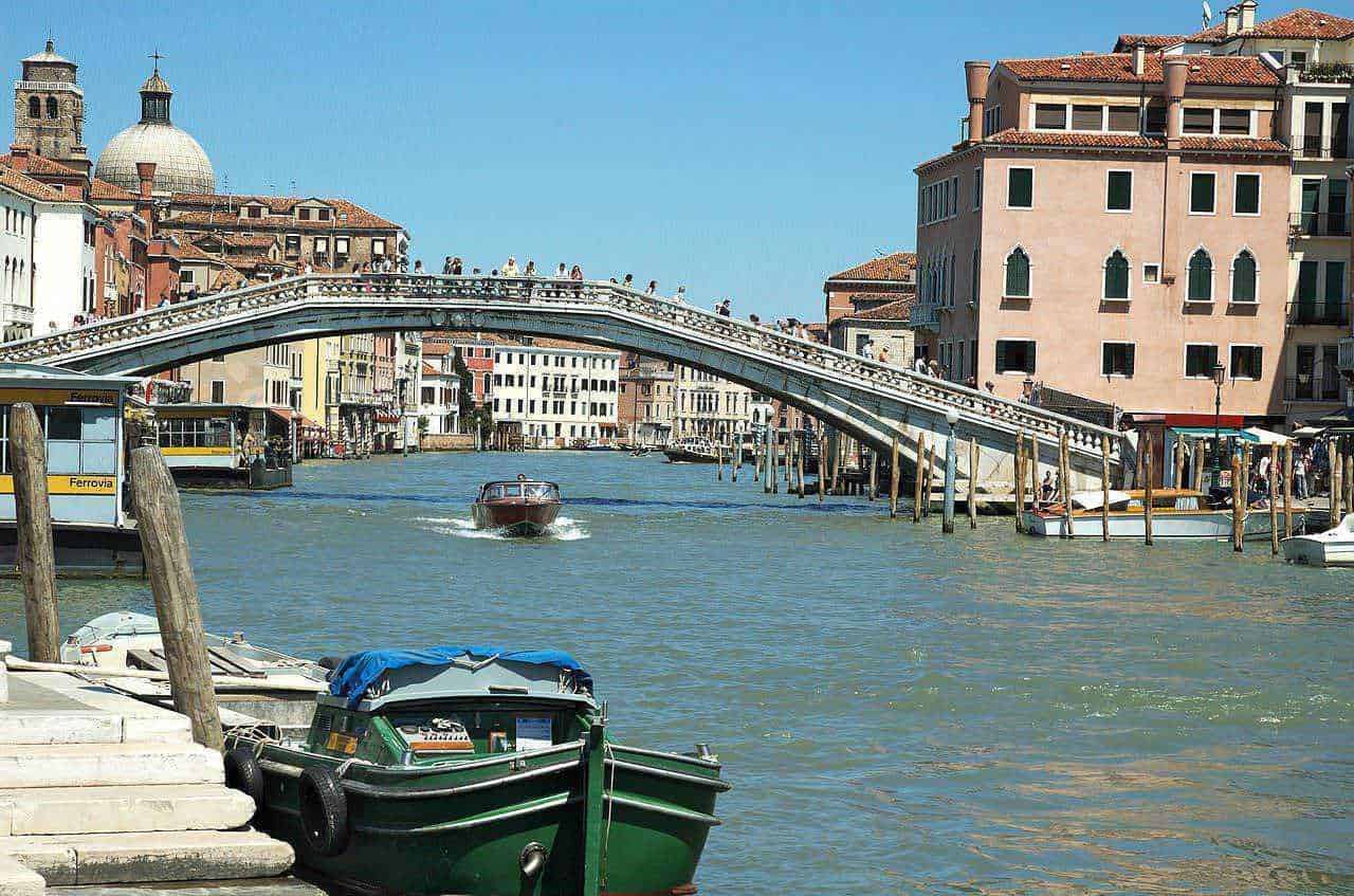 Venedig Ponte di Rialto con gondole e palazzi storici sotto cielo blu soleggiato, atmosfera romantica e turistica, immagini di viaggio e cultura veneziana, destinazione turistica ideale.