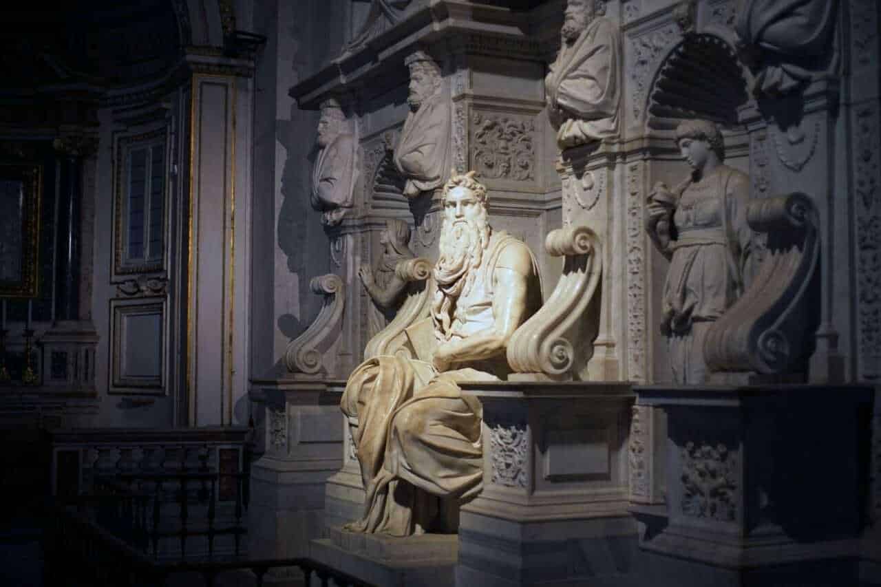 Scultura barocca di un saggio con barba lunga all’interno di un museo storico, decorazioni artistiche e dettagli in marmo bianco.