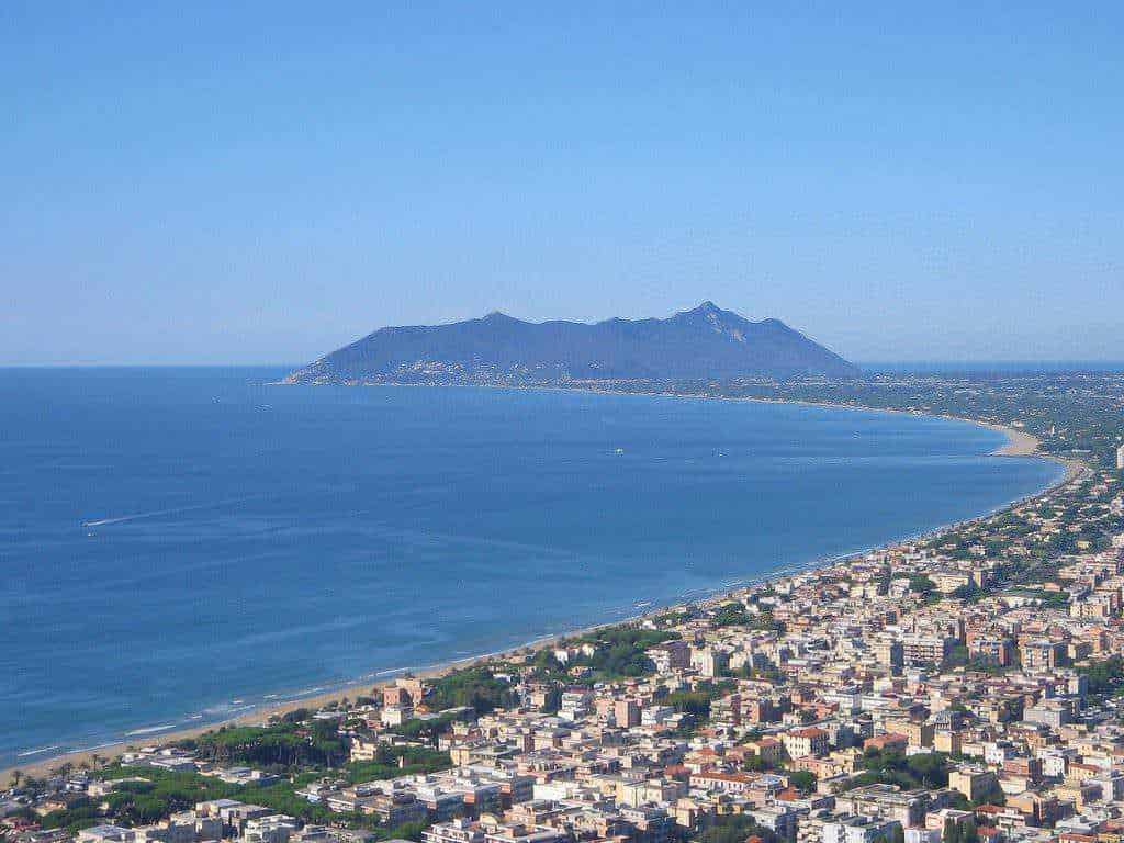 Appunti Sul Blog - Panorama della città sul mare con montagna sullo sfondo, vista aerea di un'area urbana costiera, spiaggia lunga e acque cristalline, ideale per contenuti di viaggio e turismo in Italia.