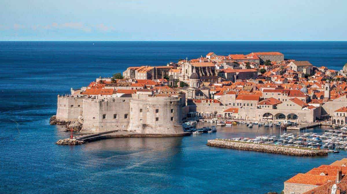 Antica città di Dubrovnik con mura storiche e porto turistico, vista panoramica sul Mar Adriatico, destinazione turistica famosa in Croazia.