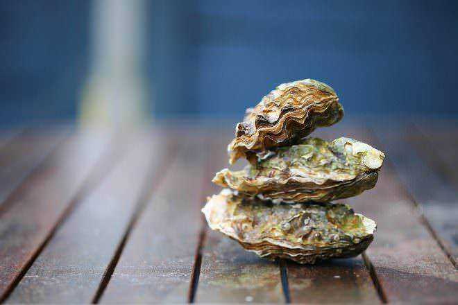 Conchiglie ostrica fresche e aperte su superficie in legno, dal mare alle ricette di cucina, simbolo di mare e mareggiata, ideale per ristorante di pesce e gastronomia di mare.