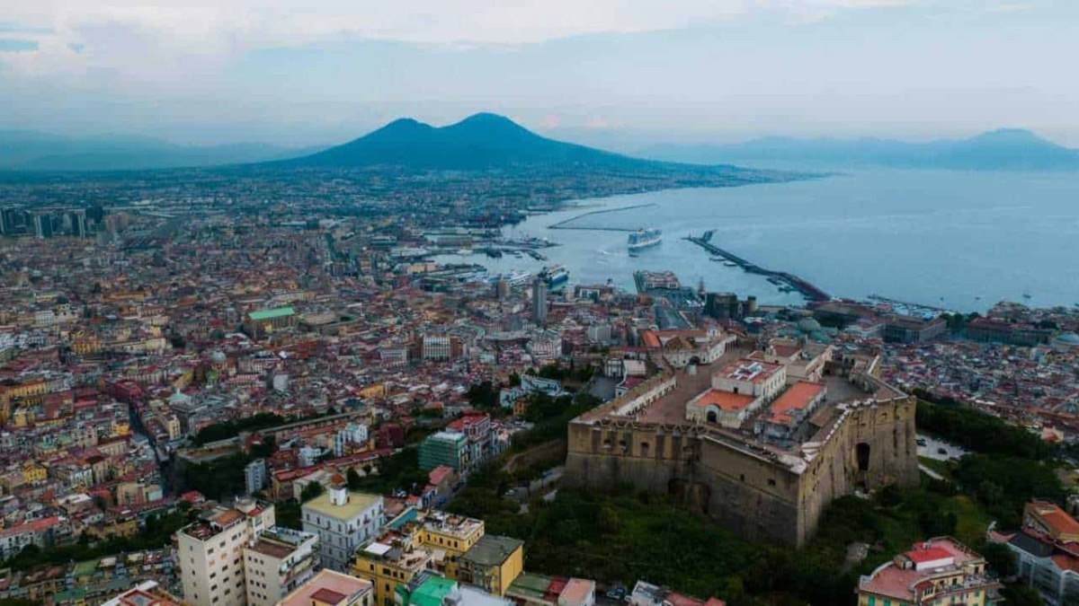 Città di Napoli con il Vesuvio sullo sfondo, vista panoramica dal Castel Sant'Elmo, con il mare, il porto e i palazzi storici, un suggestivo panorama urbano e naturale.