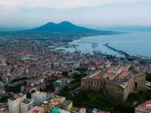 Città di Napoli con il Vesuvio sullo sfondo, vista panoramica dal Castel Sant'Elmo, con il mare, il porto e i palazzi storici, un suggestivo panorama urbano e naturale.