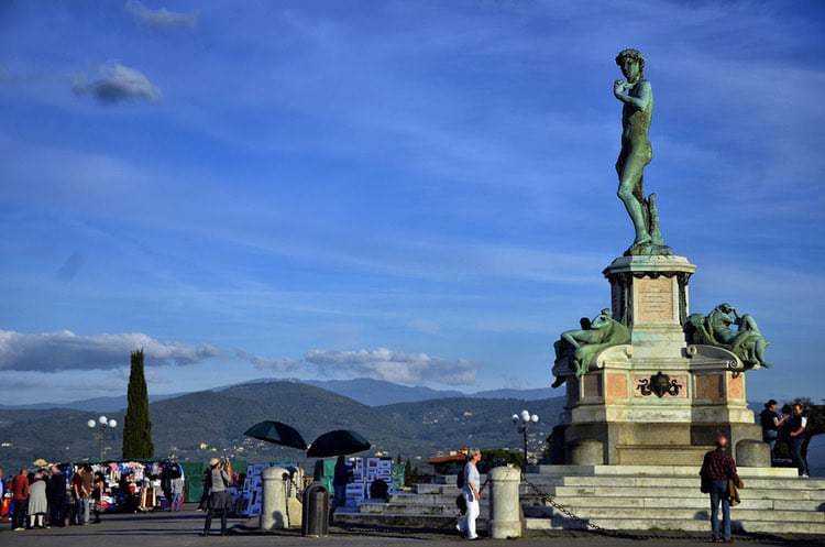 Statua di un famoso monumento storico sul lungolago di Lugano, in Svizzera, con passeggiata e persone che godono del panorama e del clima soleggiato sul Lago di Lugano.