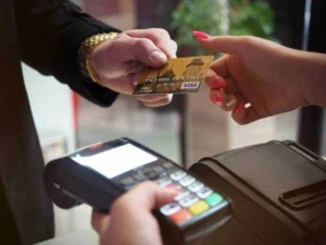 Pagamento contactless con carta di credito presso punto vendita. Tecnologia moderna per transazioni rapide e sicure, senza contatto tra cliente e cassiere.