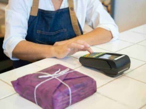 Pagamento contactless con POS in negozio, donna che effettua pagamento senza contatto.Pagamento digitale, smart payment, commercio elettronico, tecnologia di pagamento, negozio modernizzato.