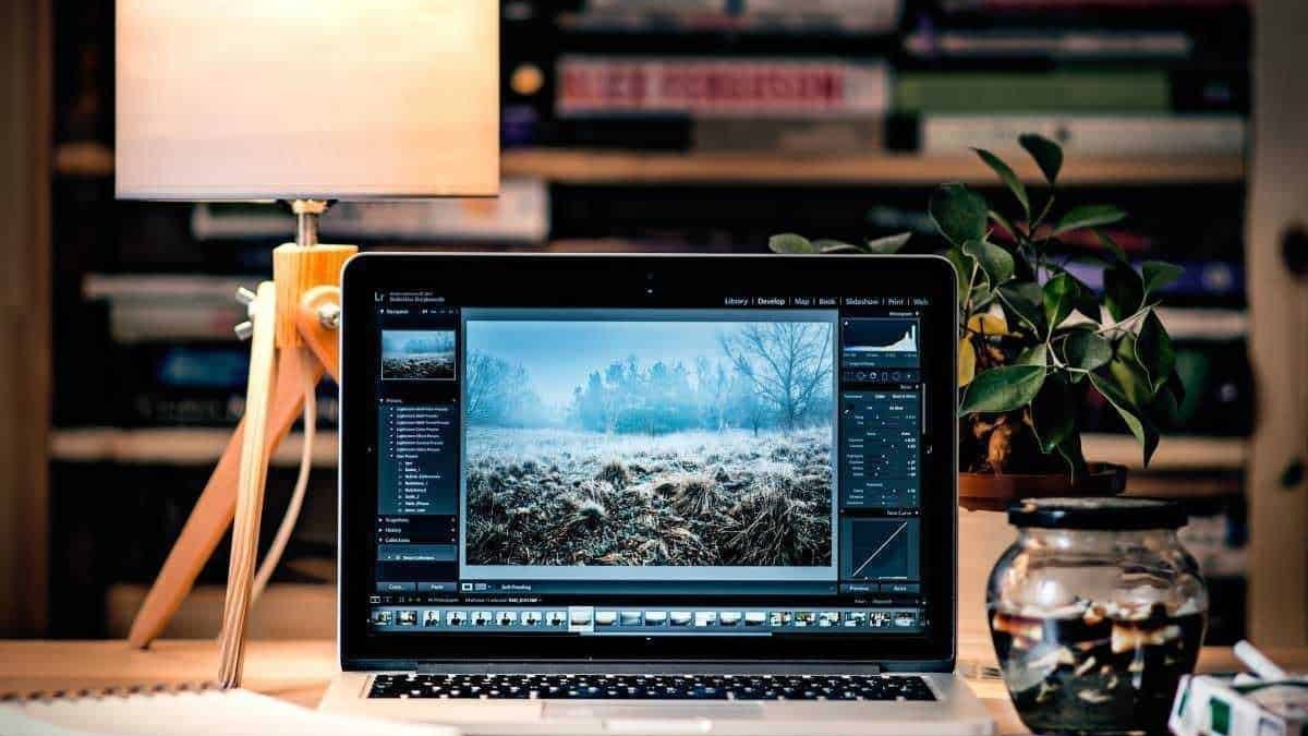 Finestra di editing fotografico su laptop con ambientazione da scrivania, documenti e lampada, rappresenta editing digitale, fotografia e lavoro creativo.
