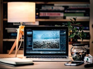 Finestra di editing fotografico su laptop con ambientazione da scrivania, documenti e lampada, rappresenta editing digitale, fotografia e lavoro creativo.