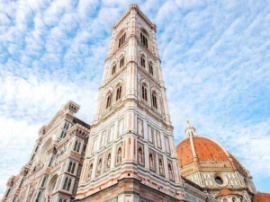 Torri di Firenze, panorama del campanile di Giotto e della Cattedrale di Santa Maria del Fiore con cielo azzurro e nuvole.
