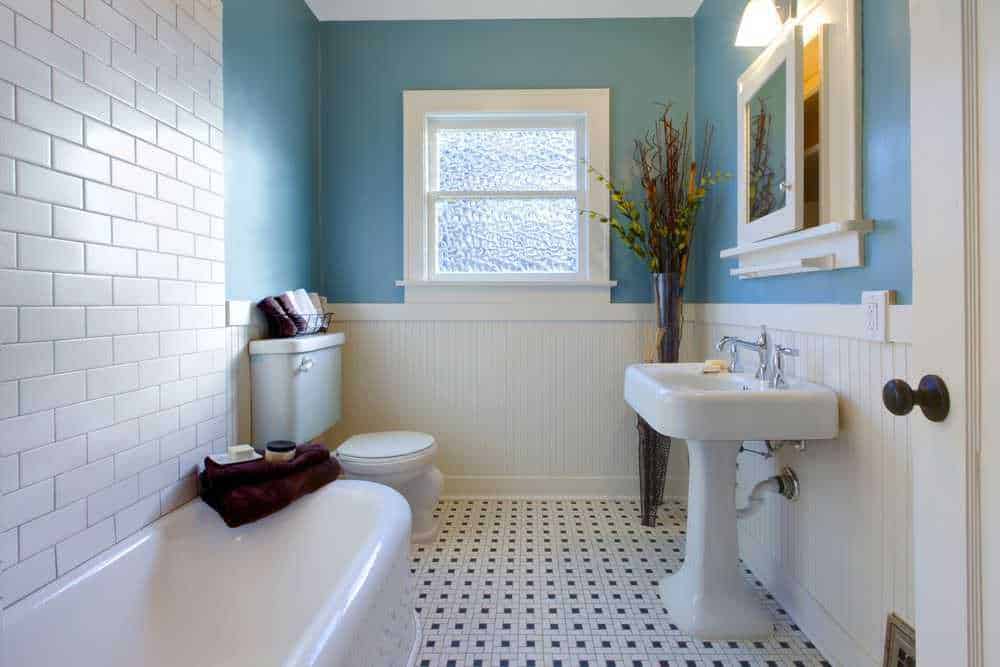 I colori più belli per la tua casa, tendenze 2023 7 Bagno con pareti azzurre e dettagli bianchi, lavabo e finestra per un ambiente luminoso e accogliente. Arredo semplice e decorazioni floreali creano un'atmosfera rilassante e pulita.