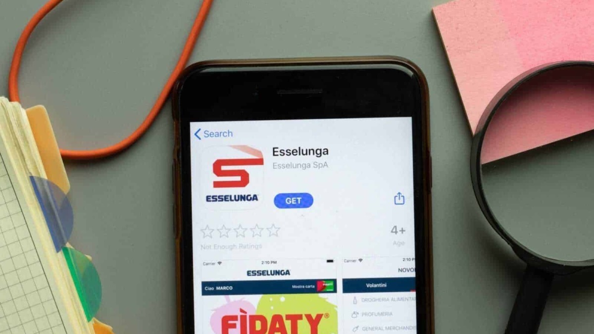 Appunti Sul Blog, immagine di uno smartphone con app Esselunga nel display, circondato da oggetti colorati e di design in un ambiente di lavoro o studio.
