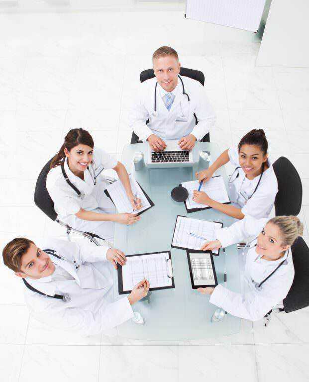 Che tipi di medico esistono? 15 specialisti e quando andare [guida]. Medici e professionisti sanitari si riuniscono in riunione medica in sala studio per discutere di diagnosi e trattamenti medici. Team multidisciplinare di medici in consultazione.