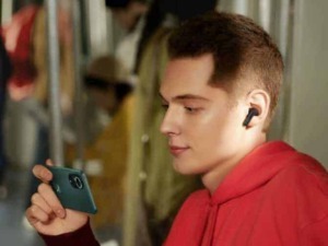FOTO di un giovane uomo seduto su un treno che utilizza uno smartphone e ascolta musica con cuffie wireless, godendosi il viaggio e la tecnologia moderna.