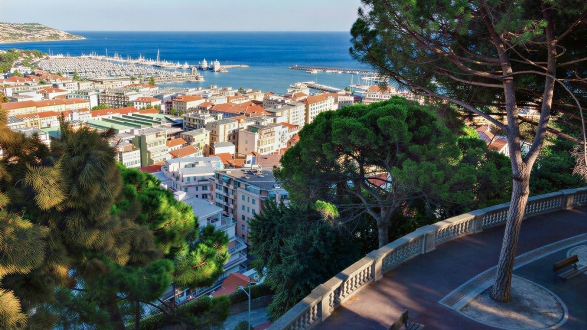 Camino panoramico con panchine e vista sulla città e sul mare di Napoli, Italia. Grandi alberi verdi adornano il percorso con una vista mozzafiato sul porto e l'orizzonte marino.