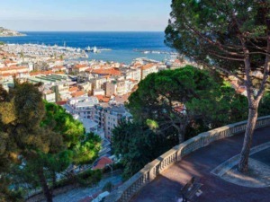 Camino panoramico con panchine e vista sulla città e sul mare di Napoli, Italia. Grandi alberi verdi adornano il percorso con una vista mozzafiato sul porto e l'orizzonte marino.
