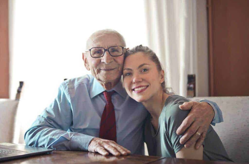 Padre e figlia anziani sorridenti abbracciati, con atmosfera familiare e affettuosa, rappresentano il tema della famiglia e dell'amore intergenerazionale.