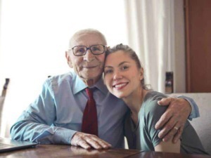 Padre e figlia anziani sorridenti abbracciati, con atmosfera familiare e affettuosa, rappresentano il tema della famiglia e dell'amore intergenerazionale.