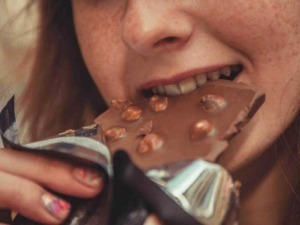 Cioccolato fondente con nocciole, assaporato da una donna, in un'immagine ravvicinata con attenzione ai dettagli del dolce.