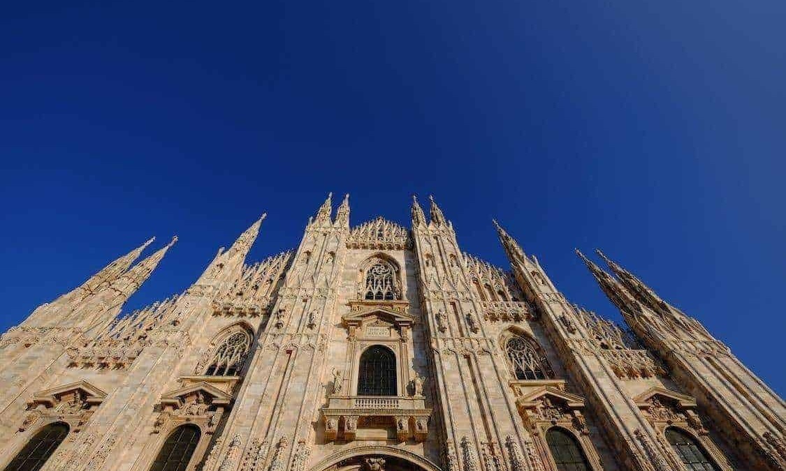 Majestosa cattedrale gotica con guglie alte e dettagli architettonici intricati contro cielo azzurro limpido.