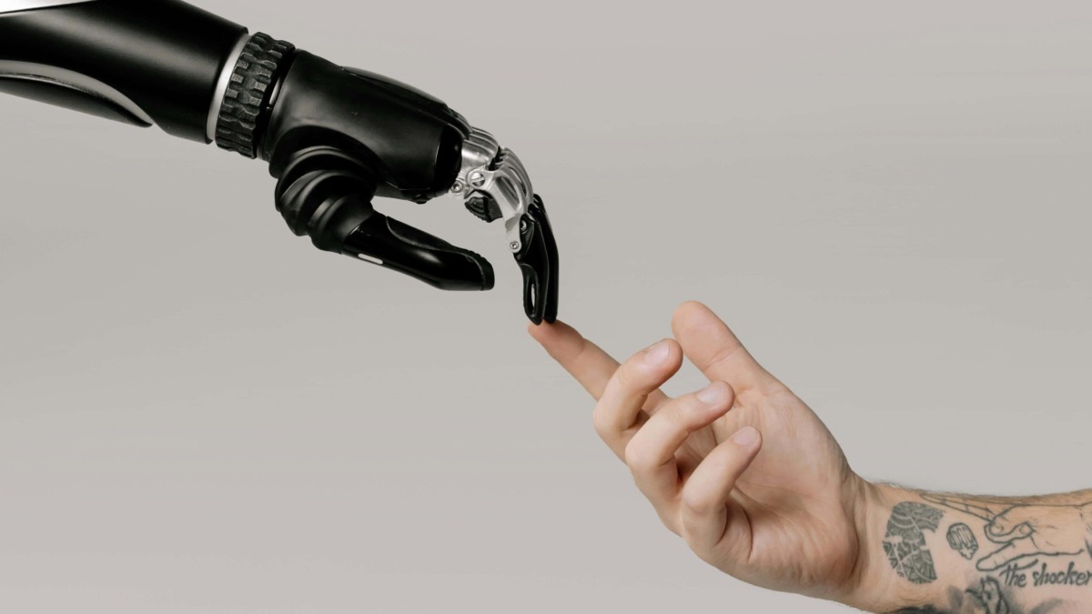 Intelligenza artificiale e umanità: robot che tocca un dito umano, simbolo di collaborazione uomo-macchina ma anche di integrazione tra tecnologia e emozioni. Immagine di confronto tra umano e robot.