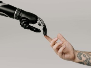 Intelligenza artificiale e umanità: robot che tocca un dito umano, simbolo di collaborazione uomo-macchina ma anche di integrazione tra tecnologia e emozioni. Immagine di confronto tra umano e robot.