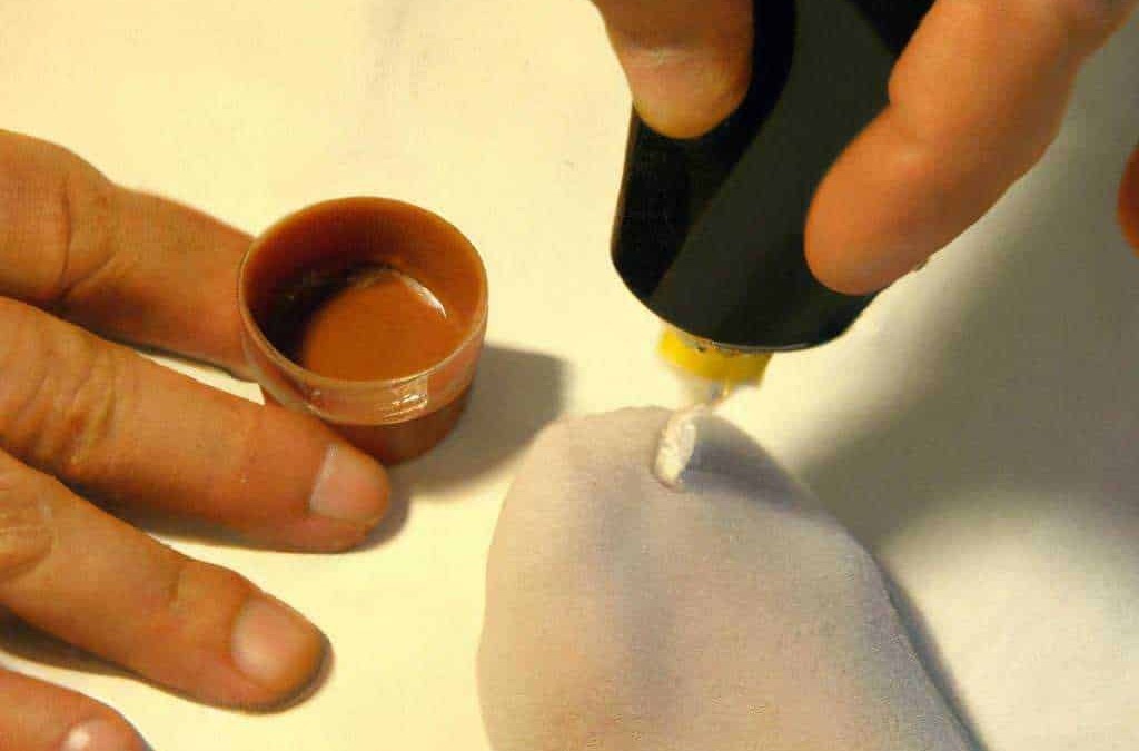 Smalto per unghie: Profondo unghie e smalto colorato applicato sulle unghie naturali. Mano che poggia su una superficie chiara mentre si stende la vernice con un pennello. Ambiente di cura delle unghie o manicure.