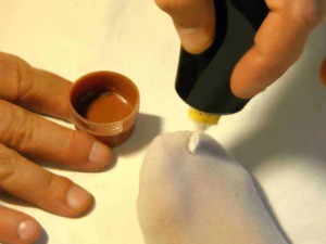 Smalto per unghie: Profondo unghie e smalto colorato applicato sulle unghie naturali. Mano che poggia su una superficie chiara mentre si stende la vernice con un pennello. Ambiente di cura delle unghie o manicure.