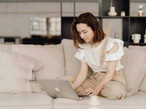 Computer portatile sul divano arredato in stile moderno, ragazza giovane che lavora da casa, ambiente accogliente e luminoso, tecnologia e lifestyle.