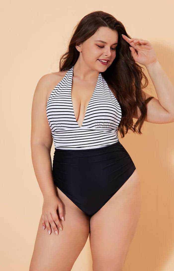 Bella donna con vestito a top e costume intero nero e bianco, in posa sorridente su sfondo beige, rappresentazione di moda e body positivity per blog di lifestyle.