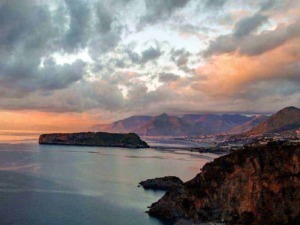 Scorcio panoramico del mare al tramonto con montagne sullo sfondo e cielo nuvoloso, vista naturale di alta qualità.