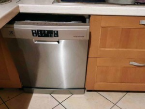 Lavatastoviglie inox integrata in cucina con mobili in legno e piano in granito. Perfetta per ottimizzare lo spazio e migliorare l'efficienza domestica.