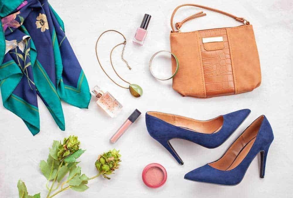 Scarpe con tacco blu, borsa in pelle beige, sciarpa colorata, profumo, smalto, collana, bracciale, rossetto e cipria, perfetti accessori moda per look femminili eleganti e di tendenza.