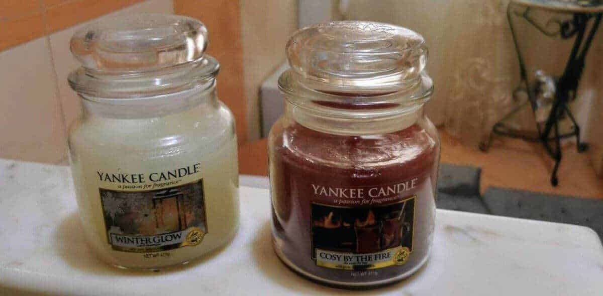 Candela Yankee Candle Winter Glow e Cosy by the Fire in vasi di vetro trasparente, atmosfera calda e accogliente, ideale per decorazioni e profumi per la casa.