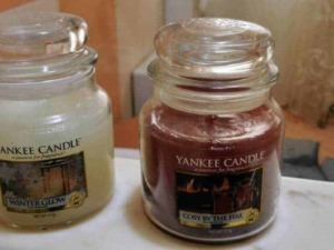 Candela Yankee Candle Winter Glow e Cosy by the Fire in vasi di vetro trasparente, atmosfera calda e accogliente, ideale per decorazioni e profumi per la casa.