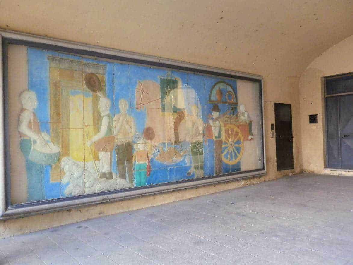 Vetro colorato con scene di vita quotidiana e scene storiche dipinte sulla vetrata, esposta su una parete di un edificio.