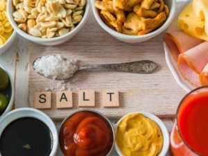 Varie spezie e condimenti come sale, ketchup e senape disposti accanto a affettati, formaggi, olive e salse su un tavolo in stile buffet italiano.