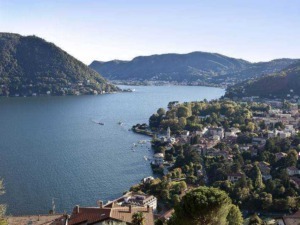 Lago di Como con panoramica sulle montagne e il paesino affacciato sulle sue rive, immerso nella natura e perfetto per una vacanza relax.