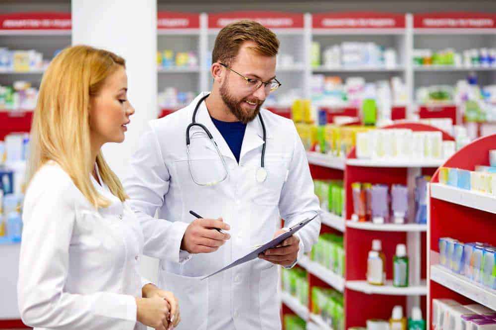Farmacisti in farmacia che consultano i farmaci sugli scaffali.