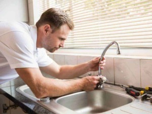 Riparazione tubature sotto il lavandino da parte di un idraulico professionista, con strumenti di lavoro e attenzione ai dettagli, per garantire un impianto idraulico efficiente.