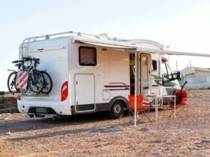Camper caravan con biciclette, sedie e tavolo all'aperto, ideale per vacanze in libertà e avventure all'aperto.