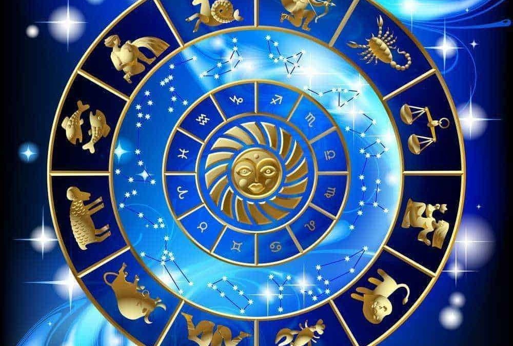 A1. Simboli zodiacali cristalli dorati disposti in un cerchio su sfondo blu stellato e cosmico.
